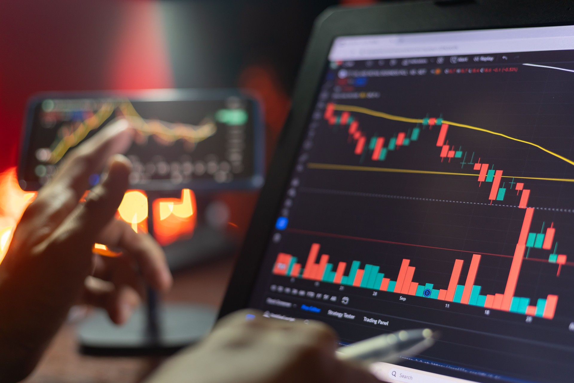 An Investor analysis the stock market exchange from the candlestick graph. Trader at home office trading on computer and using mobile phone. Financial and broker agent investment concept.